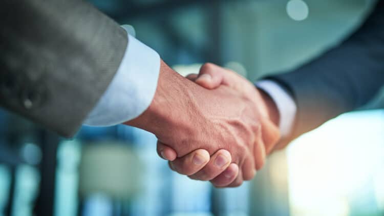 Close-up of a handshake between two business professionals in a corporate setting.