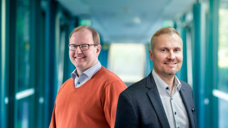 Professors Aarno Pärssinen and Mika Ylianttila from the University of Oulu, smiling in a modern corridor, recognised for their IEEE Fellow awards.