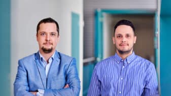 Konstantin Mikhaylov (left) and Onel López (right), newly promoted Associate Professors at CWC, University of Oulu, are standing in the corridor of the Centre for Wireless Communications.